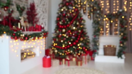 Wall Mural - Defocused blurred background with white room interior in red tones with New Year tree decorated, present boxes and artificial fireplace