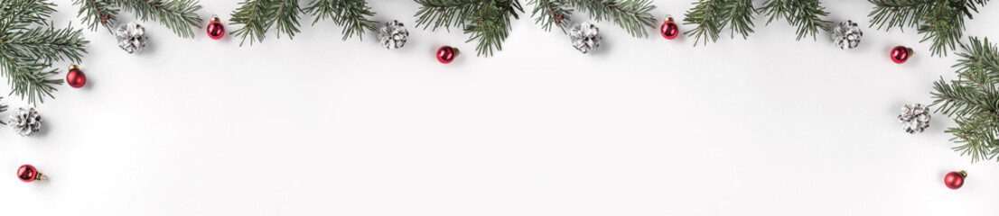 creative frame made of christmas fir branches on white background with red decoration, pine cones. x