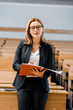 © LIGHTFIELD STUDIOS - female university professor looking at camera, holding journal and writing in classroom