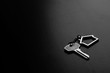 © sundaemorning - Home key with house keyring on black wood table in dark tone, real estate concept