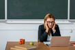 © LIGHTFIELD STUDIOS - female teacher sitting at computer desk and having headache in class