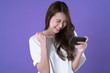 Asian woman play mobile game on smartphone and win, white t-shirt clothing, purple background