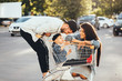 © teksomolika - Young parents put their son in a cart and have fun in the parking.