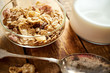 © superelaks - Healthy morning breakfast bowl full of organic granola with a spoon and a jug of milk on an old wooden table