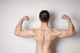 shirtless young man flexing biceps and back muscles 