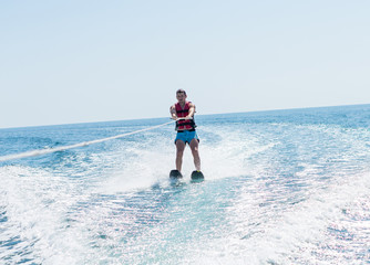 Young man glides on water skiing on the waves on the sea, ocean. Healthy lifestyle. Positive human emotions, joy. Family are spending time at tropical ocean in the day time. Miami beach.