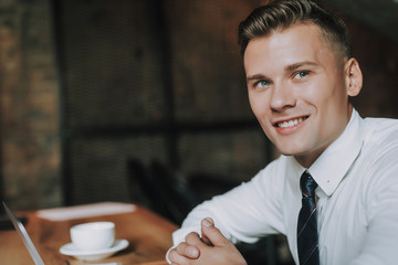 Wall Mural - Concept of success and well-being. Close up portrait of handsome young businessman working on portable computer. Copy space on left