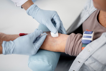 Wall Mural - Careful doctor collecting blood sample from the arm of his patient and using vacuum collection needle