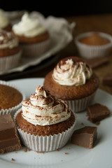 Chocolate cupcakes with whipped cream on rustic wooden table. Homemade dessert.