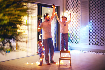 happy family, father with sons decorate open space patio area with christmas garlands