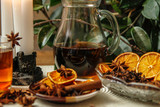 Fototapeta  - Beautiful composition with anise, cloves, cinnamon stick and powder, tea and dried orange. Wooden table, rustic background and candle light. Close-up.