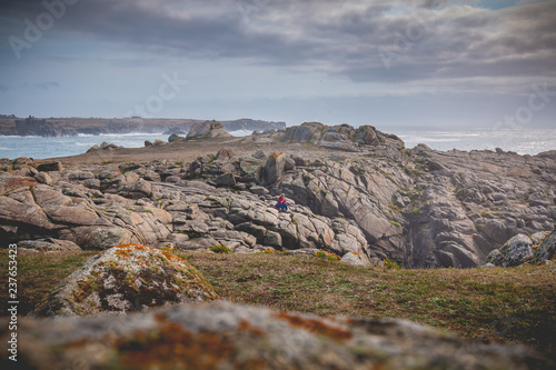 Fotografia young woman sitting on rocks of the island of Yeu
