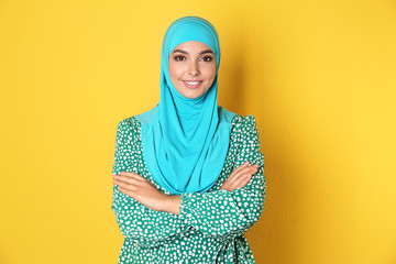 Portrait of young Muslim woman in hijab against color background