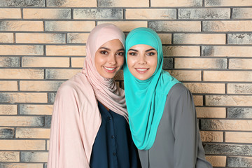 Canvas Print - Portrait of young Muslim women in hijabs against brick wall