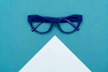 Top view flat lay, modern blue eye glasses on pastel paper background