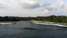 Drone Elevating Above Waves And Surfers In A Beach Cove Called Wong Tong. Most Consistant Reef Break In The Area On The Remote Island Of Simeulue, Off The Coast Of North Sumatra In Indonesia.