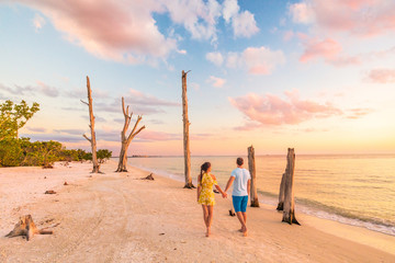 Couple walking on beach at sunset romantic travel getaway, idyllic Florida destination, Lovers key beach state park in the gulf of Mexico. Woman and man holding hands relaxing. Southwest Florida.