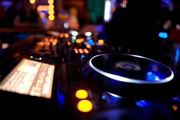 In selective focus of Pro dj controller.The DJ console deejay mixing desk at music party in nightclub with colored disco lights. Close up view