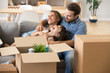 © fizkes - Multi-ethnic family spend time together sitting on couch in living room have fun play with little preschool daughter surrounded by cardboard on boxes at home. Buying new house moving mortgage concept
