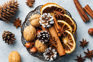 Wall Mural - Winter food ingredients nuts cones oranges cinnamon star anise in a bowl. Rustic style.