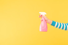 Female Hand Holding Bright Pink Cleanser Sprayer On Yellow Background. Cleaning Housework And Household Chores