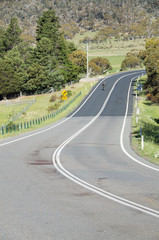 Large blood stain on rural road after wildlife roadkill with biker riding off into the distance