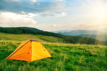 Wall Mural - orange tourist tent in the mountains under bright sun