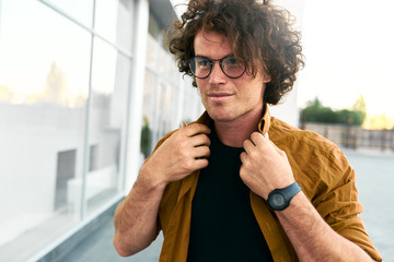 Poster - Outdoor portrait of happy young hipster man stundent wears shirt and wirstwatch walking on the street. Smart male posing outside in the city. Copy space for your text. People and business concept