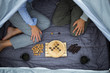 © Westend61 - Couple sitting in tent playing board game, partial view