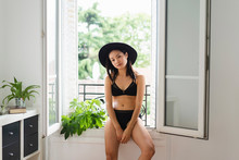 Portrait Of Attractive Young Woman Wearing Hat And Lingerie Sitting At The Window
