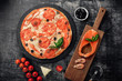 Pizza with cheese, trout, tomatoes, olives and shrimps on chalk board.