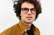 © iuricazac - Closeup shot of handsome serious young man posing for advertisement wears round glasses, looking aside, isolated on white wall outdoor. Portrait of smart student male. People emotion concept
