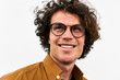 © Z A C - Happy cheerful man smiling and posing for advertisement wears round glasses, looking aside, on white wall outdoor. Closeup portrait of smart student male with curly hair. People emotion concept