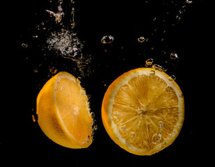 Wall Mural - slices of oranges on a black background in water splashes