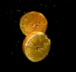 Wall Mural - slices of oranges on a black background in water splashes