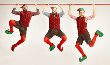 The Happy Smiling Friendly Men Dressed Like A Funny Gnome Or Elf Hanging On An Isolated Gray Studio Background. The Winter, Holiday, Christmas Concept