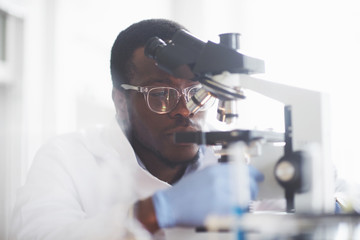 The scientist works with a microscope in a laboratory conducting experiments and formulas.