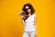 © opolja - Portrait of laughing young woman in eyeglasses taking pictures on retro vintage photo camera isolated on bright yellow background. People sincere emotions, lifestyle concept. Advertising area.