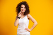 © opolja - Young model expressing emotions while posing on indoor photoshoot. Stylish curly woman having fun in yellow studio