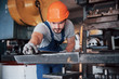 © standret - Portrait of a young worker in a hard hat at a large metalworking plant. The engineer serves the machines and manufactures parts for gas equipment