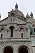 Basilica of the Sacred Heart (Sacre Coeur). Paris, France, Montmartre. Facade with statues, archs, dome and towers. Rainy day, grey sky.