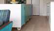 Movable kitchen island on industrial castor wheels, retro design, painted in blue and green ombre colours. Sofa in foreground