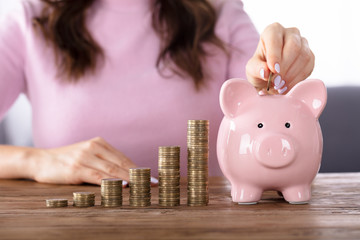 Woman Inserting Coin In Piggybank