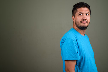 Bearded Persian man wearing blue shirt against colored backgroun