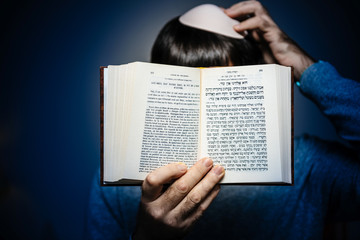 Jewish male wearing Kippah praying reading Bi-lingual Hebrew French mahzor prayer book from 1920 used on the High Holy Days of Rosh Hashanah and Yom Kippur - blue vignette.