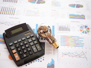 Wall Mural - top view light bulb with coin and calculator on business graph. concept of cost reduction and reduce