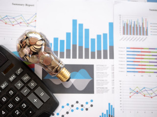 Wall Mural - top view light bulb with coin and calculator on business graph. concept of cost reduction and reduce