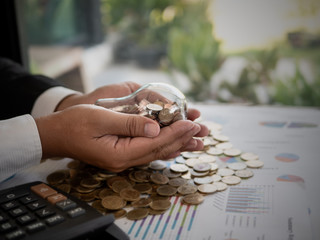 Wall Mural - hands of businessman holding a light bulb with coin. the idea of ​​reducing costs and reduce energy 