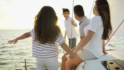 Wall Mural - Young ethnic Latino family on vacation enjoying carefree lifestyle sailing the ocean on luxury yacht sun flare 