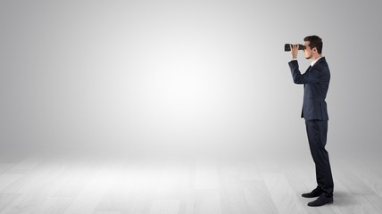 Wall Mural - businessman looking forward with binoculars in an empty space